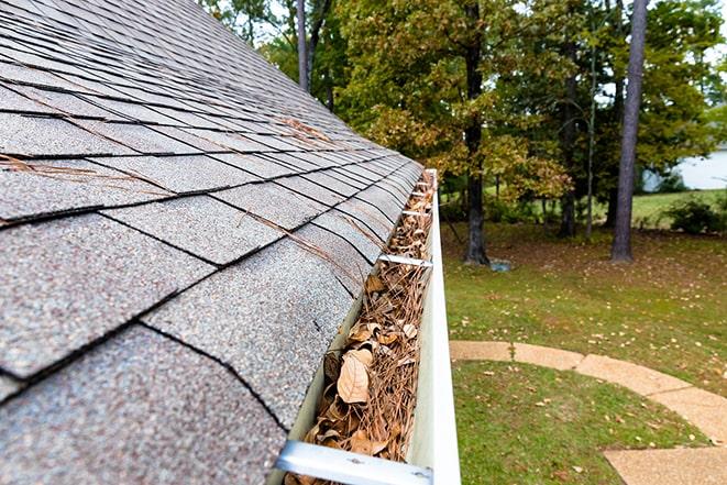 technician using power washer to clear clogged gutters